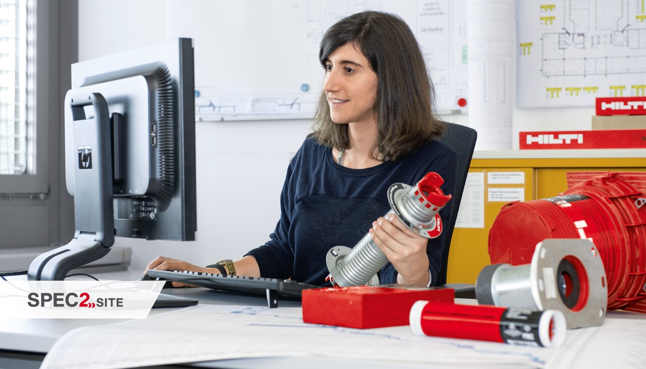 Ein Ingenieur hält eine Brandschutzlösung in der Hand und schaut dabei auf einen Computerbildschirm