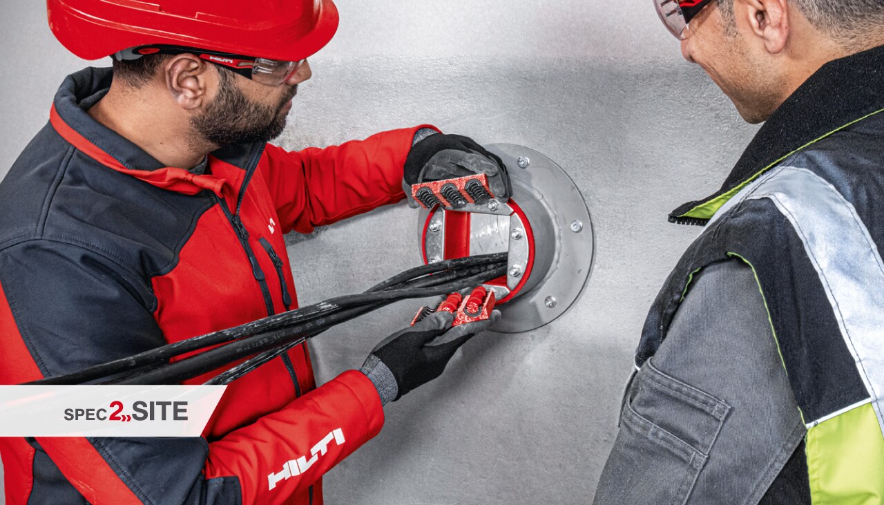 Ein Hilti Außendiensttechniker zeigt einem Kunden eine Brandschutzhülse für Elektroinstallationen