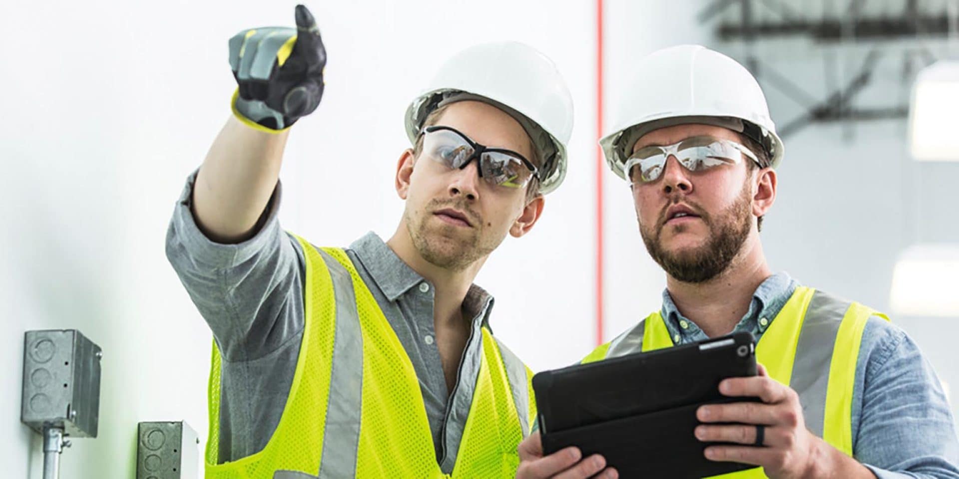 two hard-hatted men with tablet on jobsite 